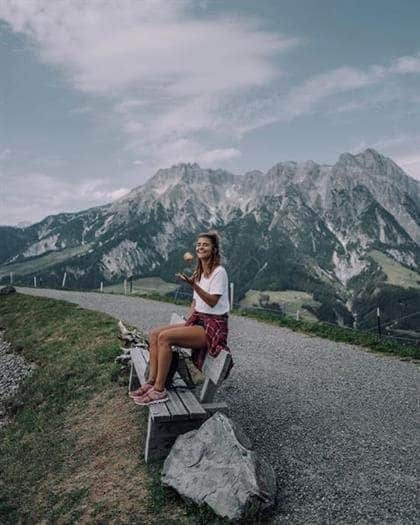 Austrian blogger Nina Radman sitting on a bench in the Alps