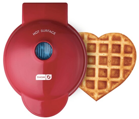 A red Dash Mini Design Heart Waffle Maker with a golden brown heart-shaped waffle 