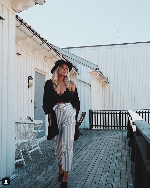 Influencer Martine Egeland walking on rooftop in striped pants and black lace bralette