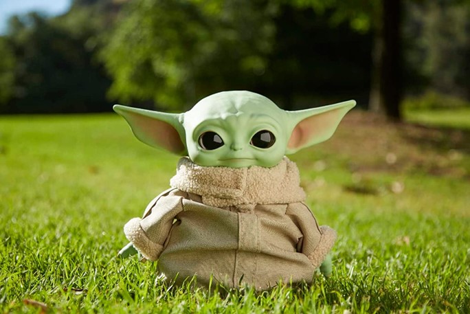 A photo of a Baby Yoda plush toy placed outside on green grass