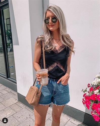 Canadian influencer Jenna Morton enjoying an iced coffee in a lace top and cut-offs