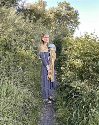 Danish influencer Emma Martiny walking on a path with her baby, surrounded by tall grass