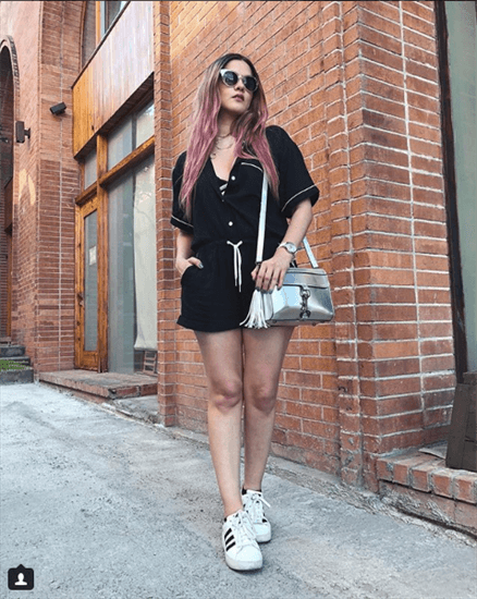 Influencer Lila Sirena wearing black button up romper and white adidas tennis shoes