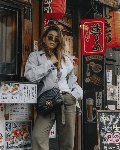 Influencer Nicoletta Reggio posing next to Chinese restaurant wearing a Gucci crossbody bag