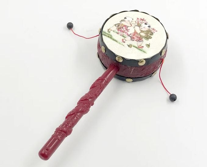 Image of a traditional Chinese spinning pellet drum with a picture of two children carrying flowers