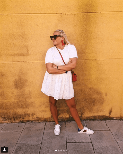 Influencer Martine Halvorsen wearing white t-shirt dress in front of yellow wall
