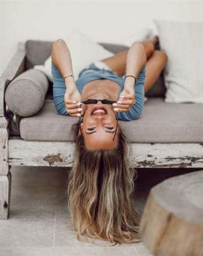 German influencer Hannah posing upside down on a couch and smiling