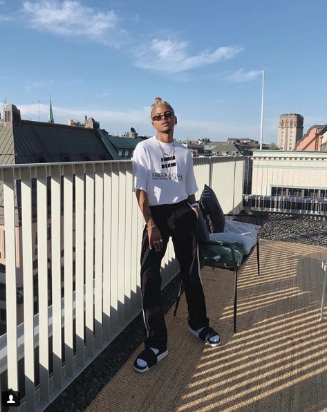 Influencer Julian Hernandez wearing slip on sandals and athletic outfit on balcony