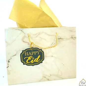 White and gold gift bag and wrapping paper with a card that says “Happy Eid”