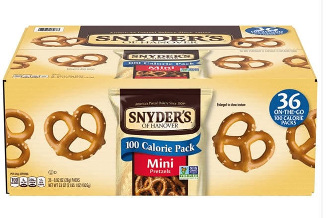 A big tan Snyder’s of Hanover pretzel box with 35 on-the-go 100 calorie packs, with the signature logo on the top and center of the box, and several classic pretzels placed all over the box