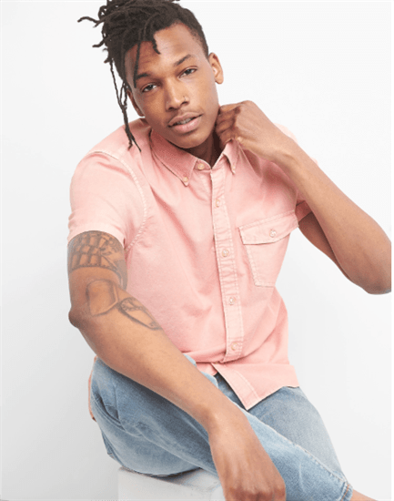 Black male wearing pink short sleeve button up shirt and jeans