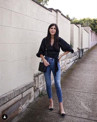 Aussie fashion influencer Jamie-Lee dressed in a black wrap shirt and cropped jeans styled with a black handbag and flats