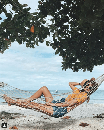 Influencer Aisa Ipac laying in net hammock on the beach