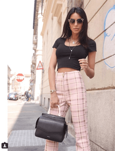 Influencer Chiara Biasi wearing black crop top and pink plaid high waisted pants