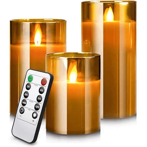 Three different-sized brown LED candles next to their gray remote control