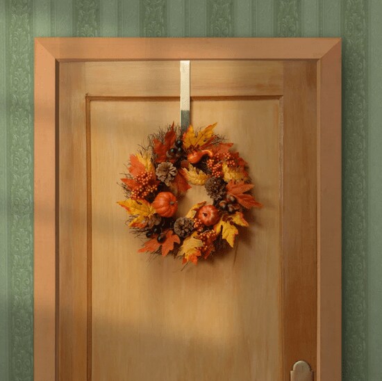 An orange, yellow, and brown The Holliday Aisle Faux Berry Foam Wreath in front of a wooden door and green wall room 