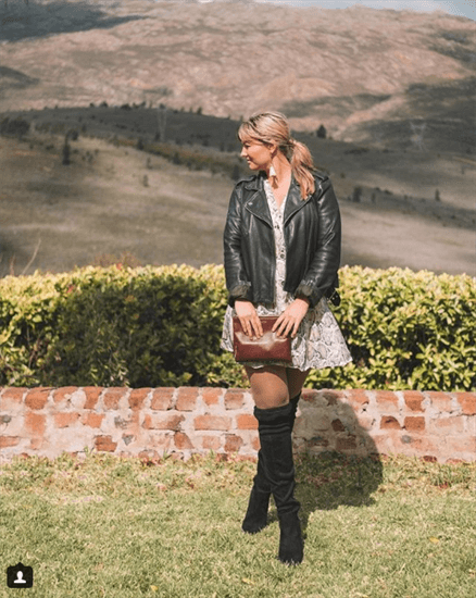 Influencer Natalie Roos wearing a dress with black blazer and black over the knee boots standing on the grass