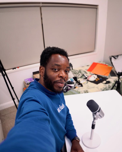 a man in a blue sweater at a table with a microphone