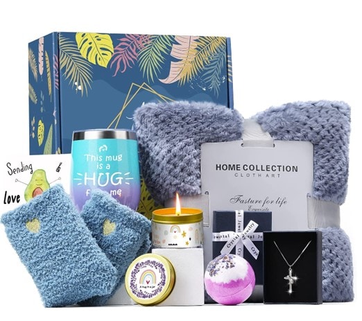 Blue-themed care package for women containing a hug mug, fuzzy socks, flannel blanket, silver cross, bath bomb, scented candle and a card