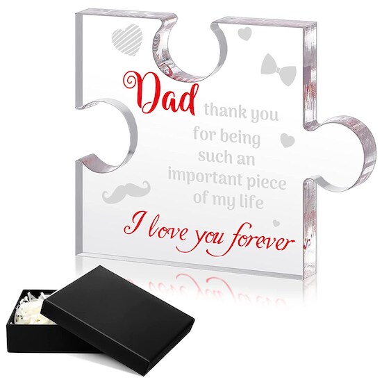 A Chitidr Father’s Day Acrylic Puzzle Piece Decoration featuring red and black words and art on the block next to a slightly open black box packaging
