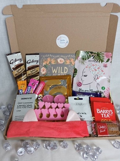 Pamper Hamper care-package box for Women with eye and face masks, toe separators, candles, candy, hot chocolate, biscuits, tea, and a card.