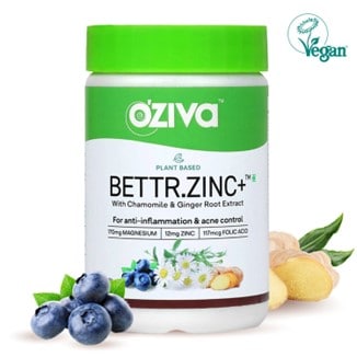 A white and green BETTR.ZINC+ bottle of Oziva’s plant-based zinc with 5 grapes in front of it and a couple of cut ginger roots in the back