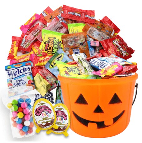 Packs of snacks and candies next to an orange carved-pumpkin-like bucket